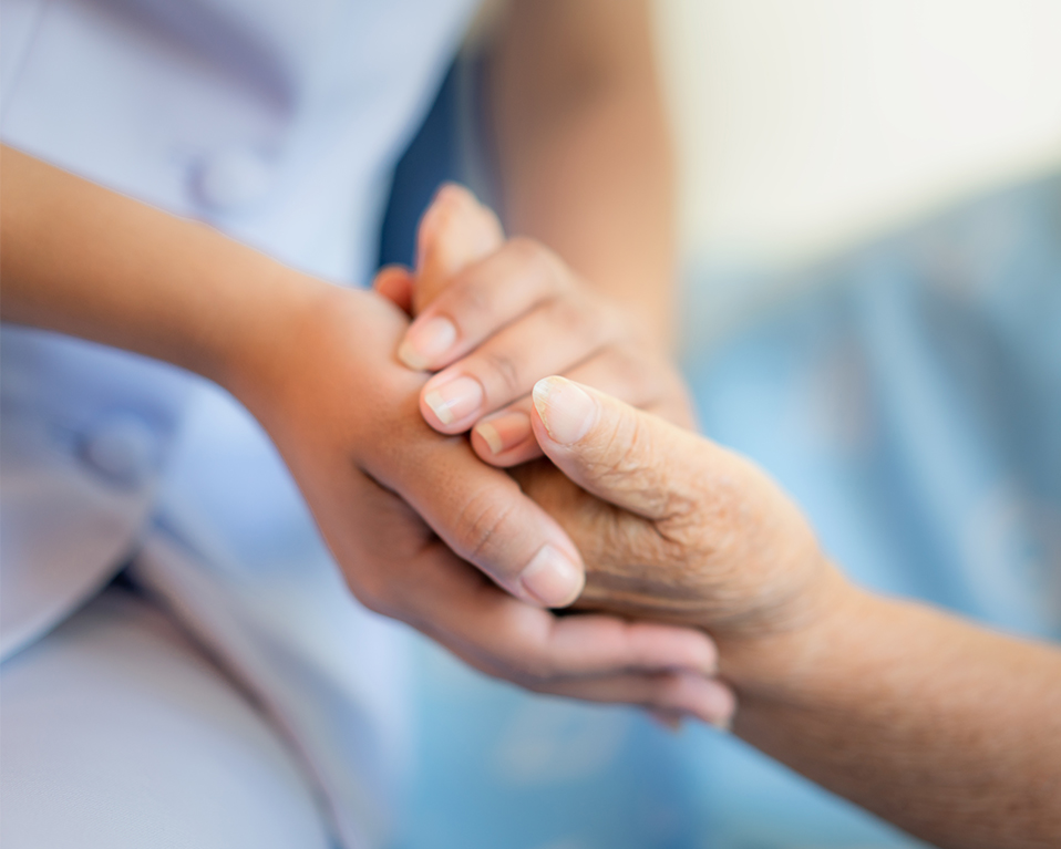 Las manos de una enfermera sujetan las de un paciente de avanzada edad