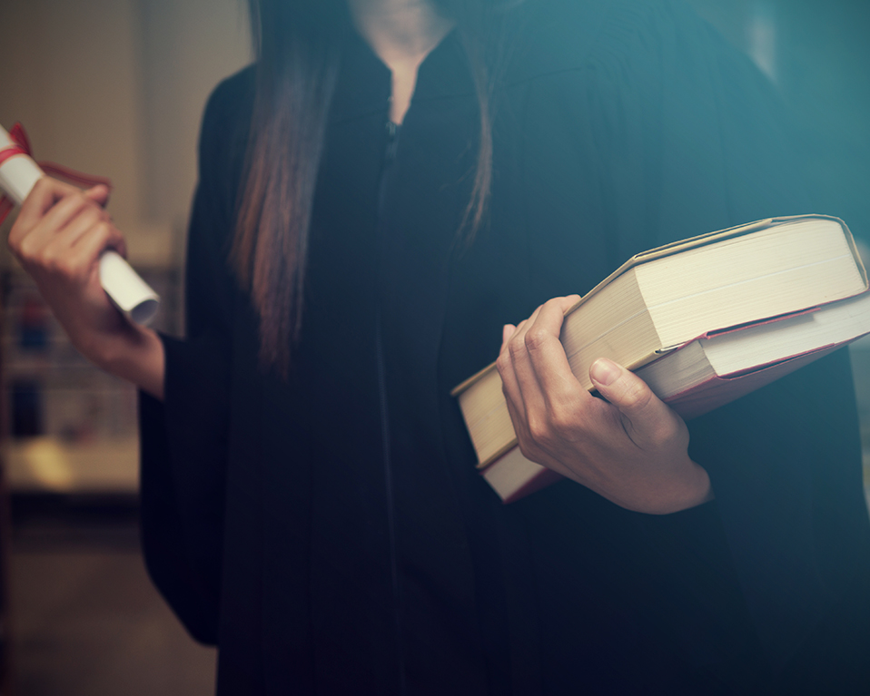 Estudiante sujetando dos libros y un diploma